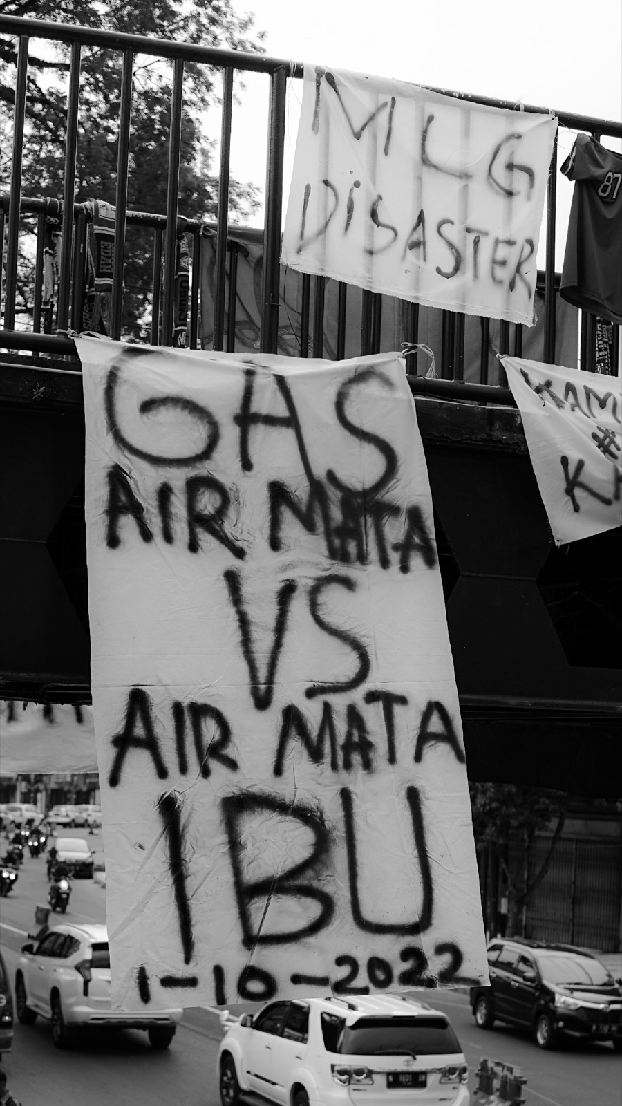 Spanduk bertuliskan Gas air mata vs air mata ibu terikat di jembatan penyeberangan di Malang